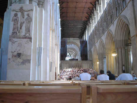 An inside view of the Cathedral and Abbey Church of St Alban with a view of the wall paintings and a choir rehearsing for a concert. Taken from the congregation towards centre crossing